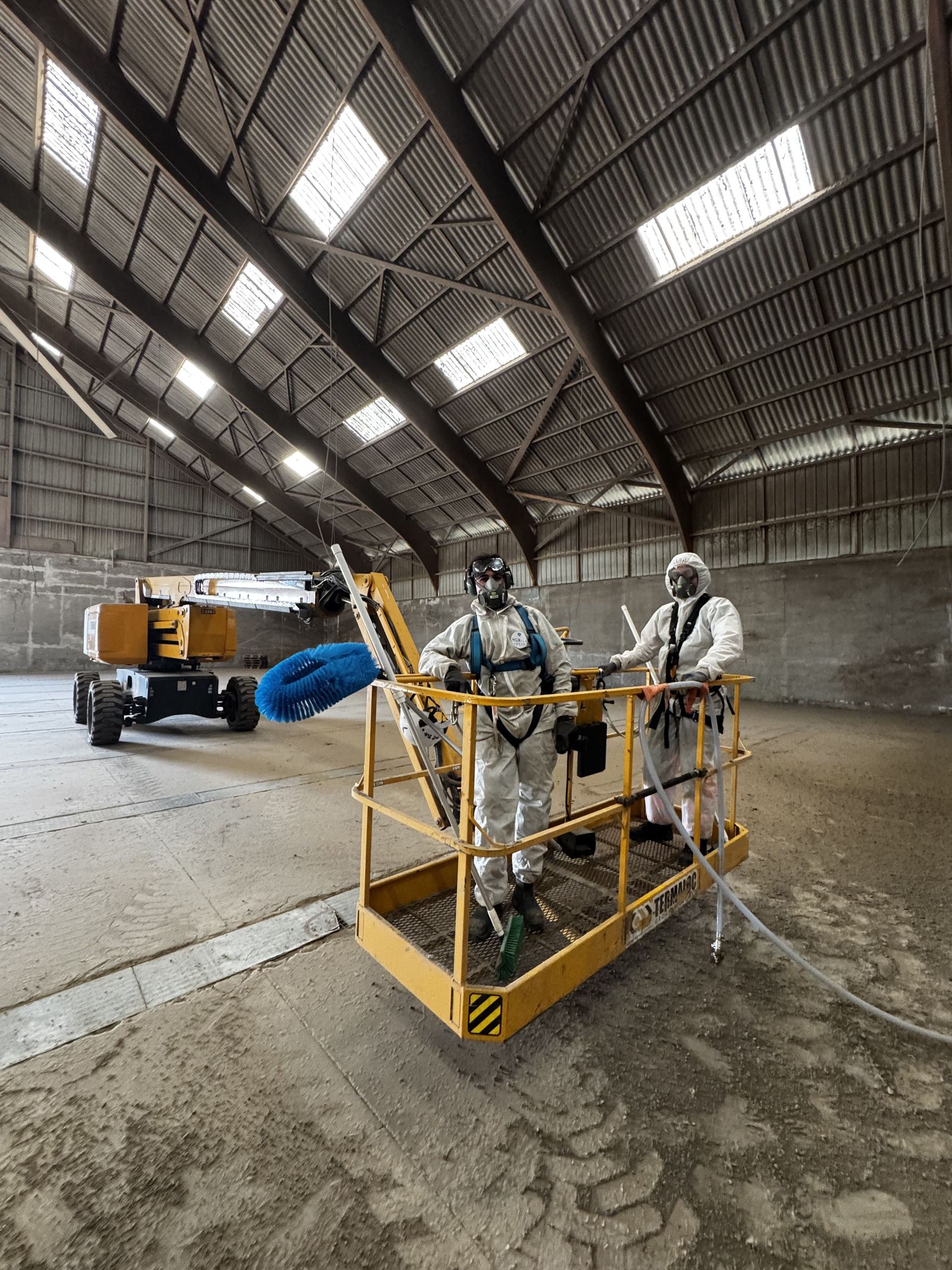 Technicien en combinaison sur nacelle élévatrice dans un entrepôt agroalimentaire