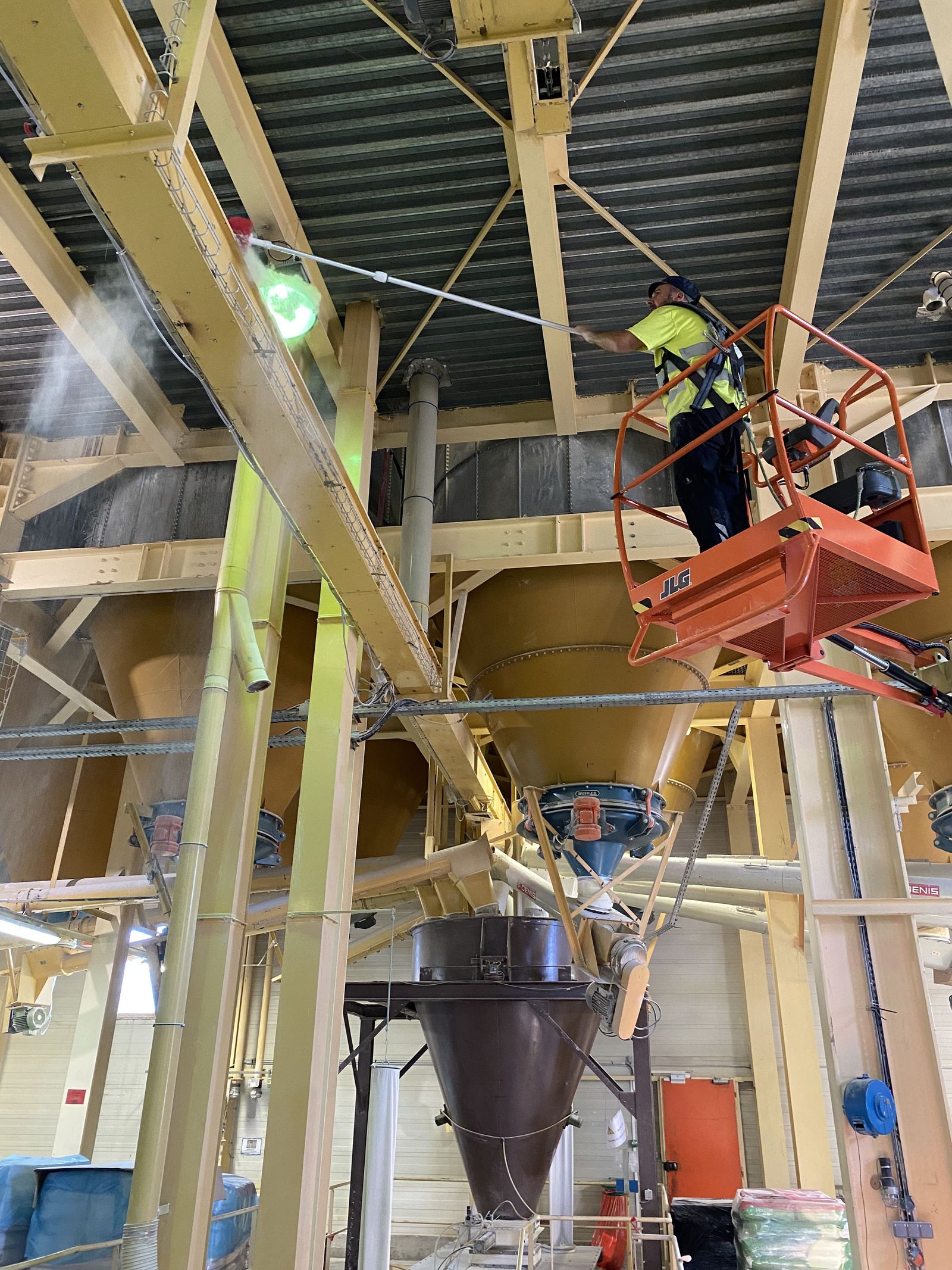 Technicien procédant au nettoyage des structures hautes d'un site industriel